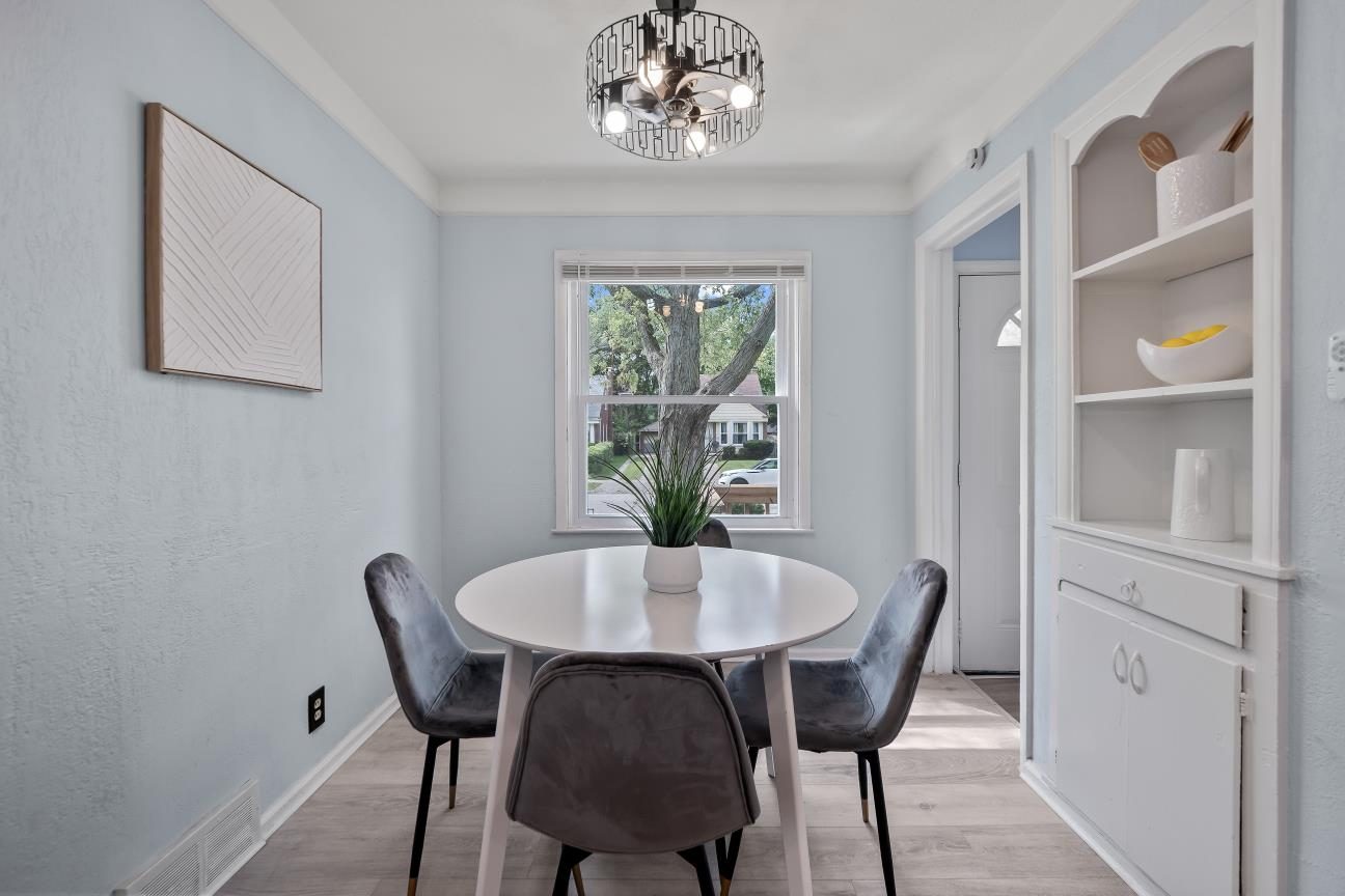 Dining room with a built-in corner cabinet, a modern ceiling light, a window to the street, and wood-look floors