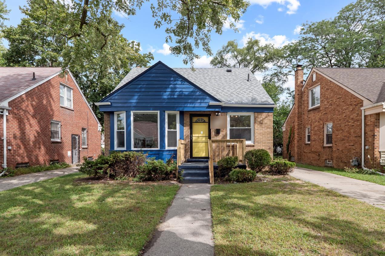 Renovated blue and brick bungalow with a yellow front door on Greydale in Detroit