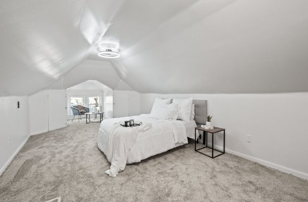 Finished upstairs bedroom under a sloped ceiling with carpet, white walls, and a ceiling light
