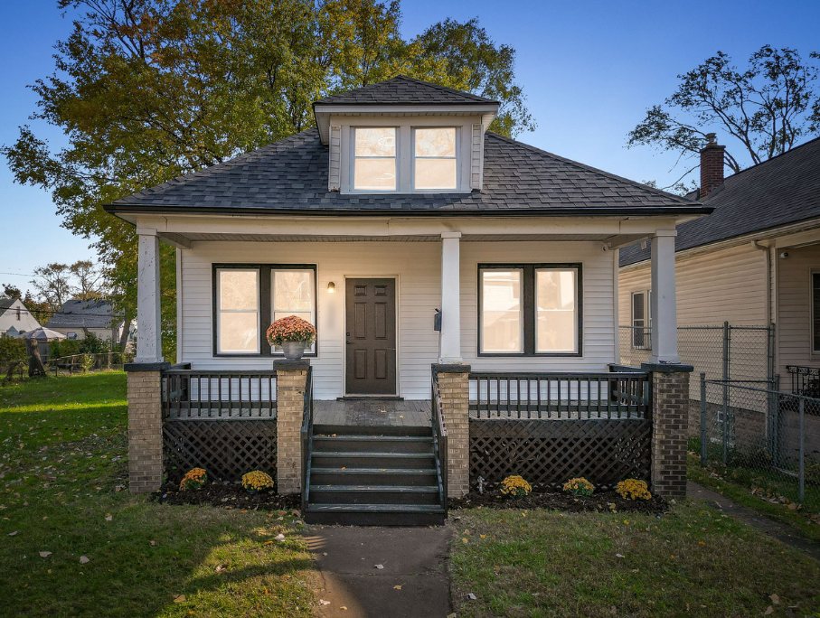Renovated Detroit bungalow on Prairie with a covered front porch, brick piers, black railings and lattice, dark front steps, and a shingled dormer