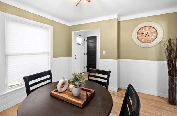 Dining room with white wainscoting, crown molding, hardwood floors, and a black interior door